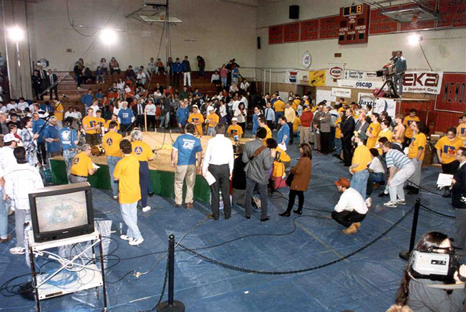 Teams and spectators around the field at the first FIRST Robotics Competition in 1992