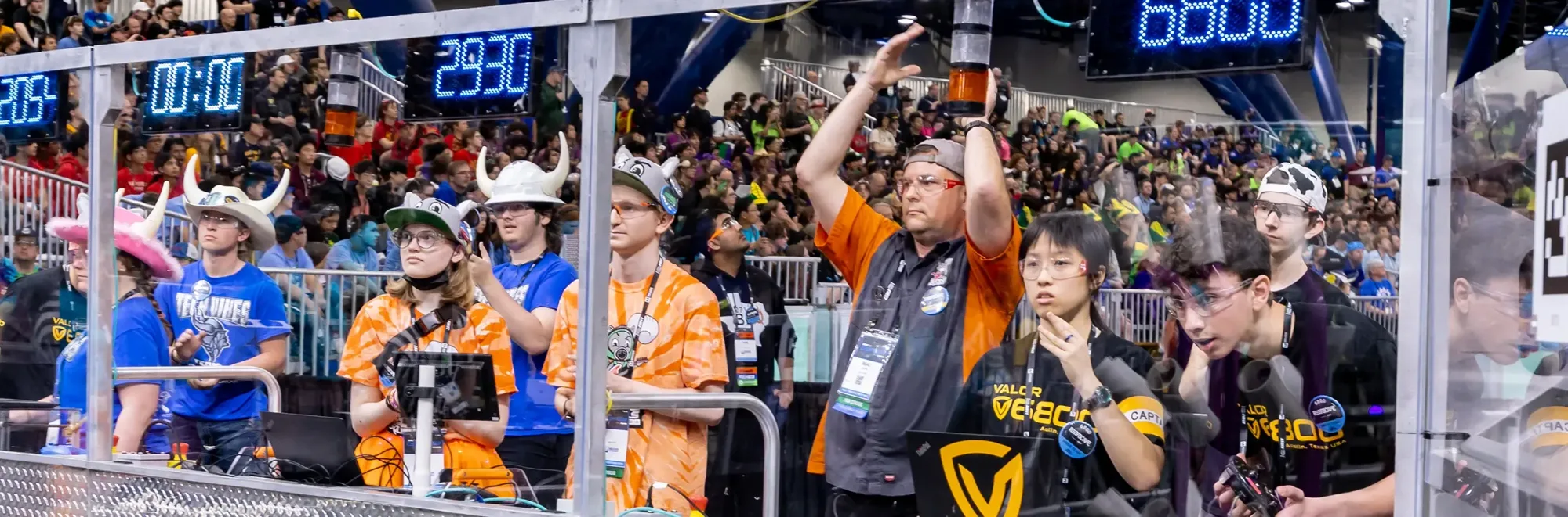 Drive teams at the field glass during a match, with a packed crowd behind them