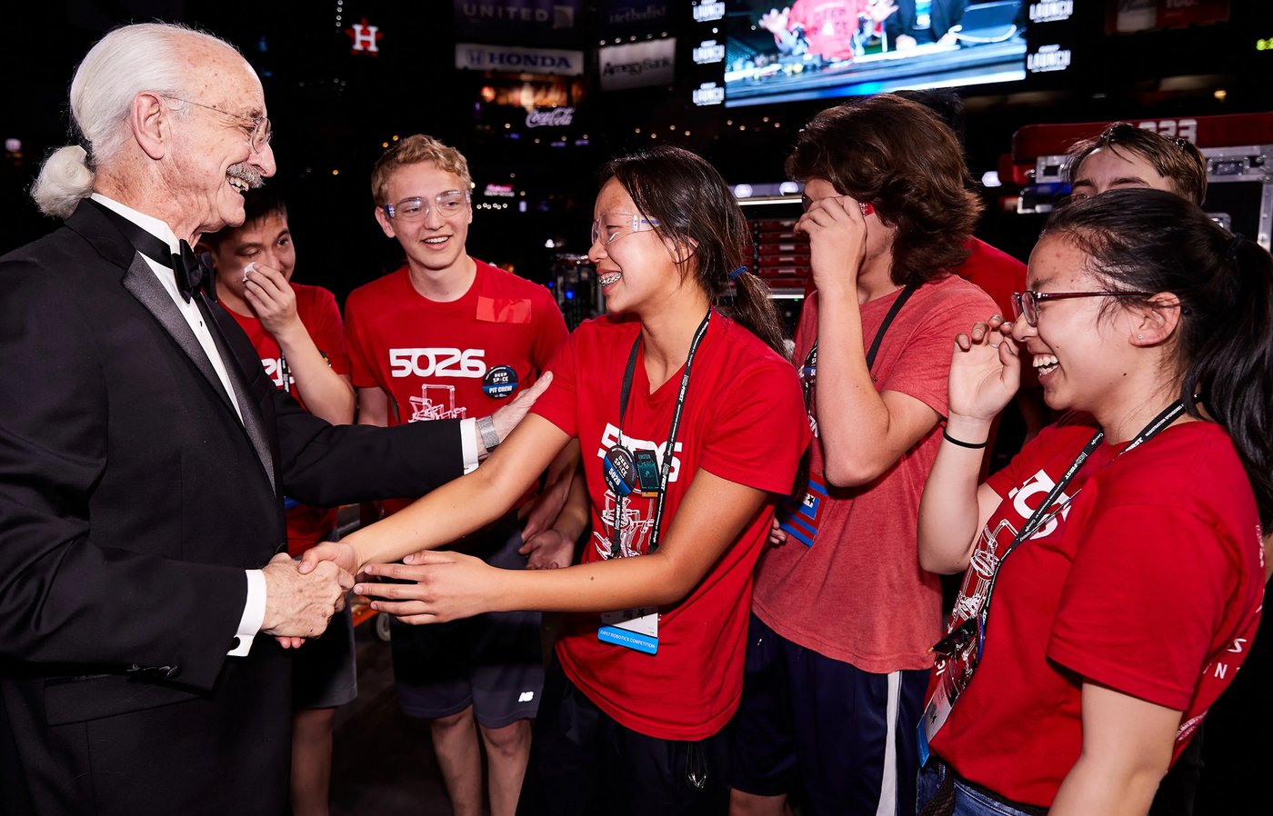 A FIRST volunteer congratulating a team of students at a competition