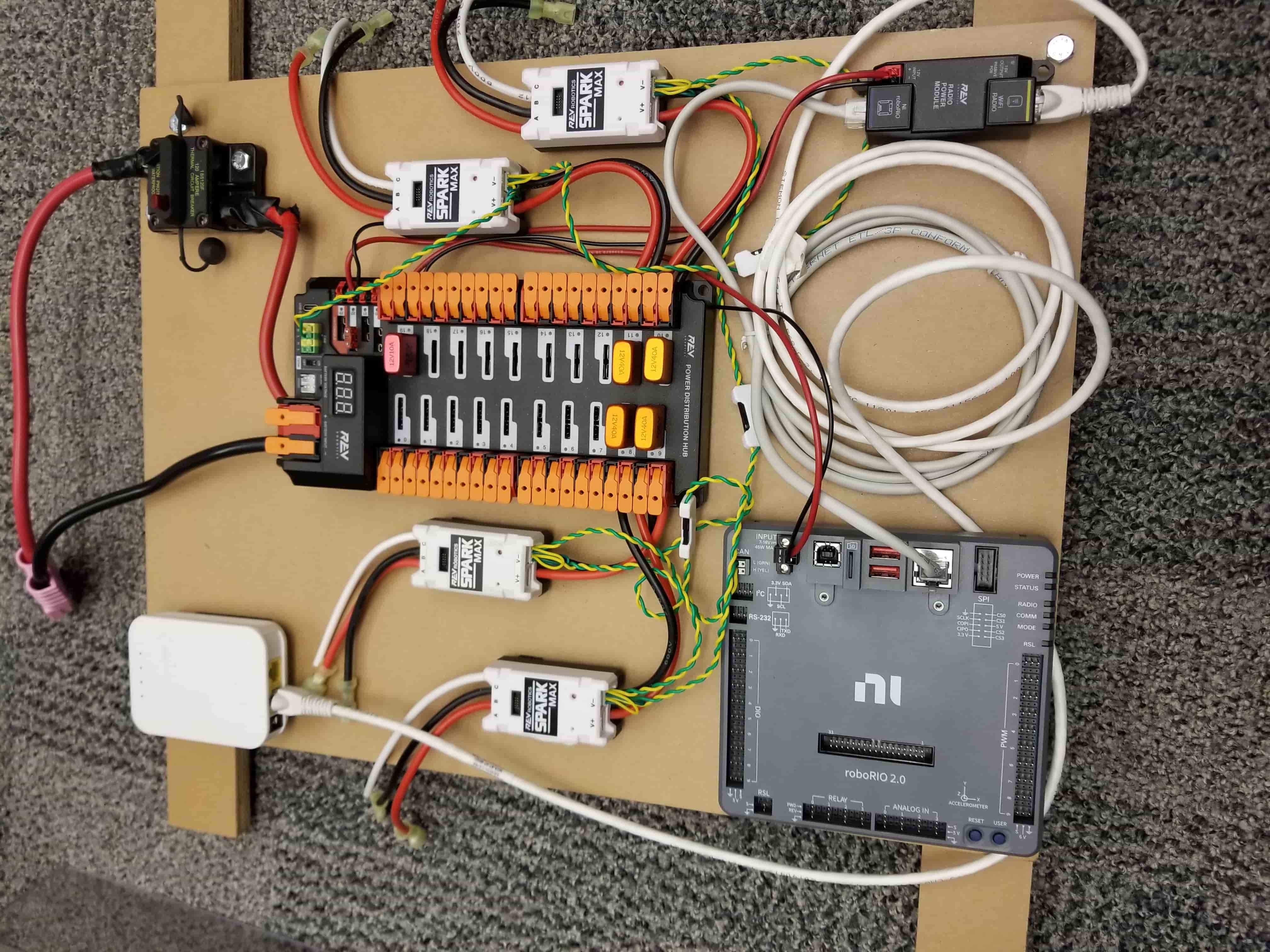 An electronics board with the main breaker, a REV Power Distribution Hub, four SPARK MAX motor controllers, a roboRIO and a radio, all wired